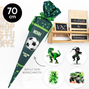 Könnte beinhalten: Eine grüne und weiße Schultüte, 70 cm hoch, mit einem Fußball-Design und dem Namen "Noah". Enthält runde Designs mit einem Dinosaurier, Ninja, Minecraft-Charakter und Monster-Truck. Mit Text.