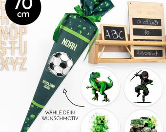 Peut inclure: Un cornet d'école vert et blanc de 70 cm de haut, avec un motif de ballon de football et le nom "Noah". Comprend des motifs circulaires avec un dinosaure, un ninja, un personnage Minecraft et un monster truck.