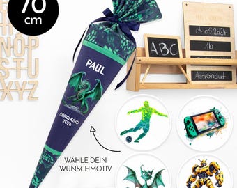 May include: A navy blue school cone, 70 cm tall, with a green dragon illustration and the name "PAUL". The cone has a green trim and a patterned top. Additional round designs feature a soccer player, a video game console, and a robot.