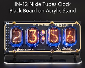 May include: A black clock with a clear acrylic stand and four Nixie tubes displaying the time 23:56. The clock has a gold trim and a black background with the text "IN-12 Nixie Tubes Clock Black Board on Acrylic Stand" at the top. The clock also has the text "GRA & AFCH" at the bottom.