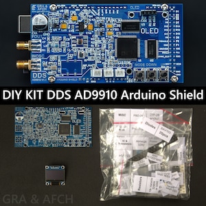 Könnte beinhalten: Ein blaues Arduino-Shield-Kit zum Bau eines DDS-AD9910-Frequenzsynthesizers. Das Kit enthält eine blaue Leiterplatte mit einem OLED-Display, einem kleinen blauen LCD-Bildschirm und einer Tüte mit elektronischen Bauteilen. Das Kit ist mit "DIY KIT DDS AD9910 Arduino Shield" beschriftet.