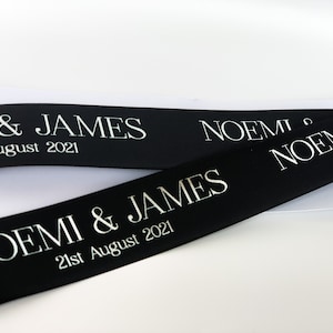 Black satin ribbon printed in white letters "Noemi & James" with date in smaller letters underneath