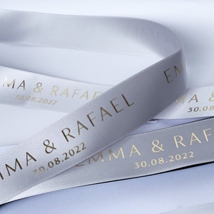 Light grey satin ribbon with gold text printed "emma & Rafael" with date underneath in smaller letters