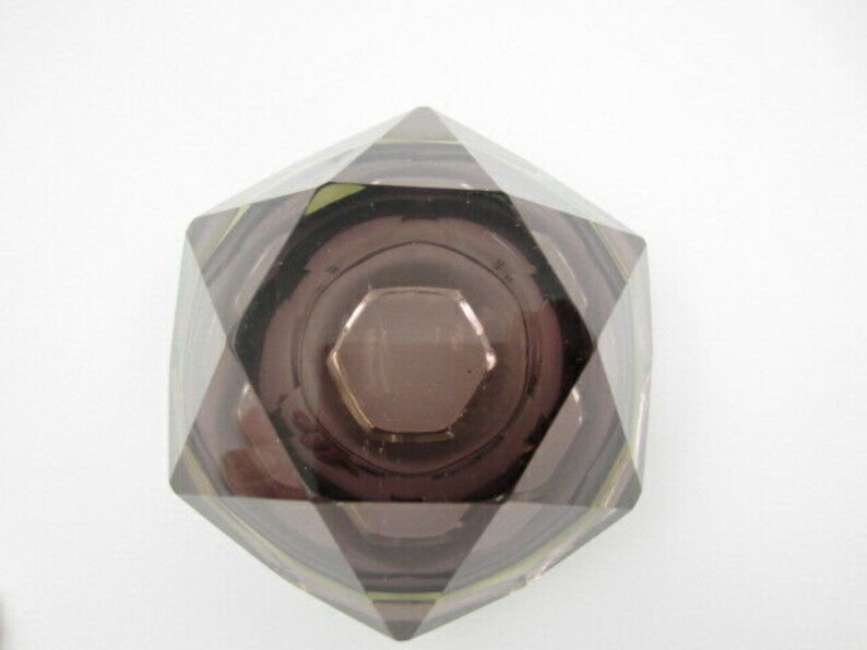 K&ouml;nnte beinhalten: Ein Aschenbecher aus klarem Glas mit geometrischem, facettiertem Design. Der Aschenbecher ist dunkelviolett und hat ein Sternmuster.