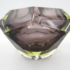 K&ouml;nnte beinhalten: Ein Aschenbecher aus violettem Glas mit geometrischem Design und gelben Akzenten.