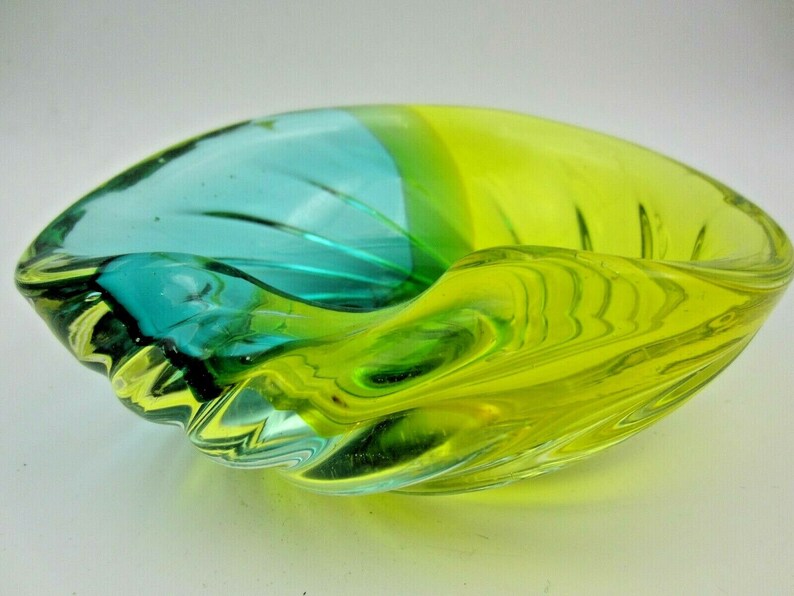 Puede incluir: Un cuenco de vidrio verde y azul con un dise&ntilde;o ondulado. El cuenco est&aacute; hecho de vidrio transparente con un remolino verde y azul.