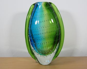 May include: A green and blue glass vase with a textured bubble design. The vase is oval shaped and has a clear glass base.
