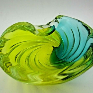 Puede incluir: Un cuenco de vidrio verde y azul con un dise&ntilde;o de espiral. El cuenco est&aacute; hecho de vidrio transparente con un degradado de color verde y azul.