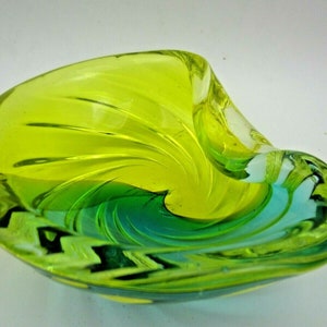 Puede incluir: Un cuenco de vidrio verde y azul con un dise&ntilde;o de espiral. El cuenco est&aacute; hecho de vidrio transparente con un patr&oacute;n de espiral verde y azul.