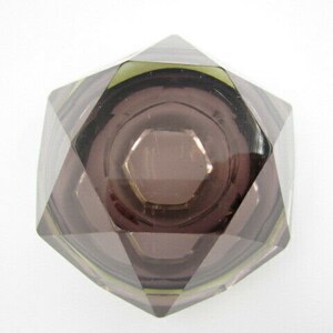 K&ouml;nnte beinhalten: Ein Aschenbecher aus violettem Glas mit geometrischem Design. Der Aschenbecher hat eine tiefe Vertiefung in der Mitte und ist aus klarem Glas mit einer violetten T&ouml;nung gefertigt.