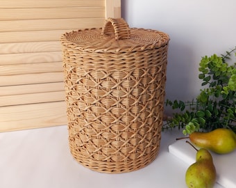 May include: A woven wicker storage basket with a lid and handle. The basket is cylindrical with a diamond pattern and is light brown in color. The lid has a handle for easy removal. The basket is suitable for storing items.