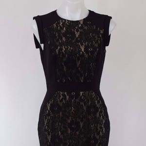 Puede incluir: Un vestido negro sin mangas con una superposici&oacute;n de encaje. El encaje es un patr&oacute;n floral y es de un tono de negro m&aacute;s claro.
