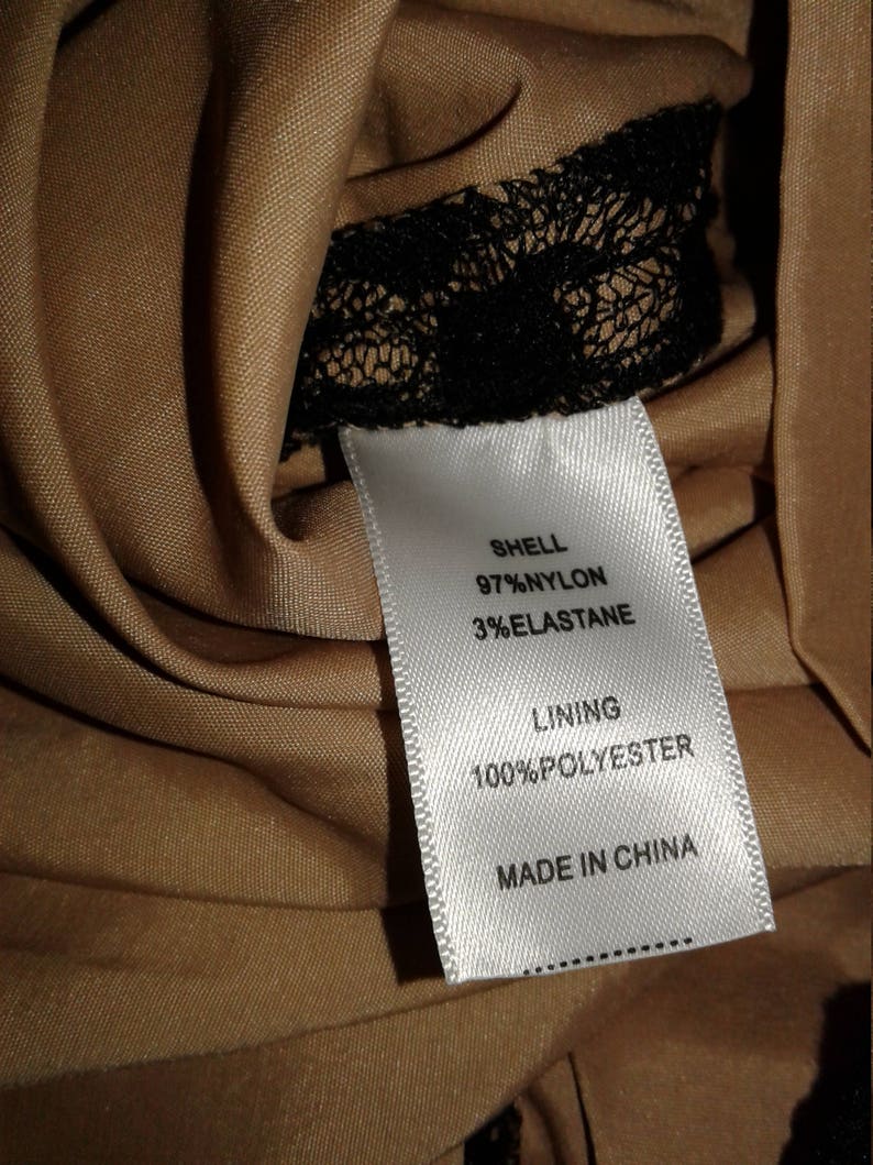 Puede incluir: Etiqueta de cuidado de la tela blanca con texto negro. La etiqueta dice "Shell 97% Nylon 3% Elastane Lining 100% Polyester Made in China".