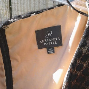 Puede incluir: Vestido de encaje negro con forro marr&oacute;n y una etiqueta negra que dice "Adrianna Papell" y "10P Hecho en China".