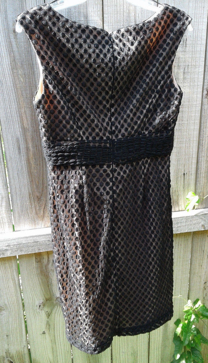 Puede incluir: Vestido negro sin mangas con estampado de lunares y una banda negra alrededor de la cintura.
