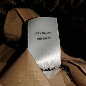 Puede incluir: Etiqueta de cuidado blanca con texto negro que dice "DRY CLEAN RN#59782".