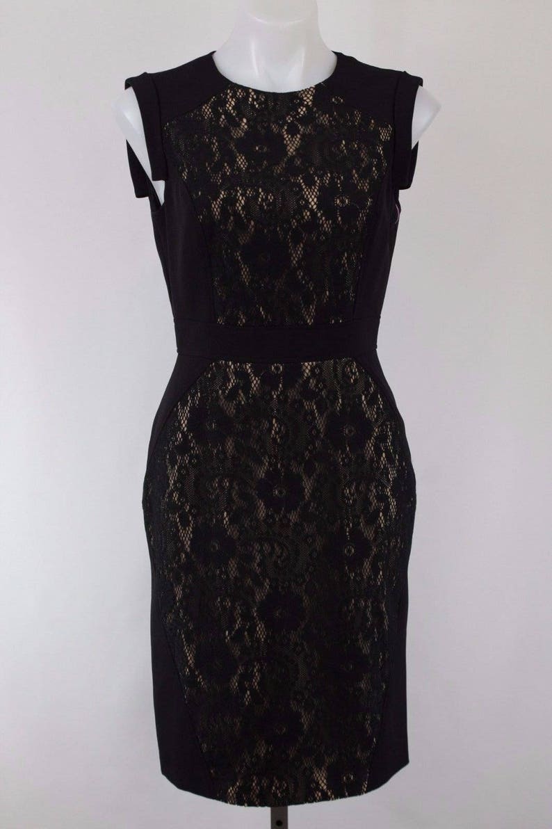 Puede incluir: Un vestido negro sin mangas con una superposici&oacute;n de encaje. El encaje es un patr&oacute;n floral y es de un tono de negro m&aacute;s claro.