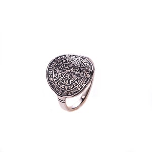 May include: A silver ring with a circular design featuring a spiral of letters and symbols. The ring is a unique piece of jewelry with a vintage aesthetic.