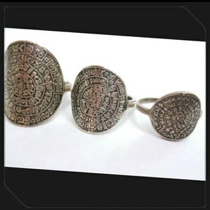 May include: Three silver rings with intricate circular designs. Each ring features a different size and a pattern of symbols and letters.