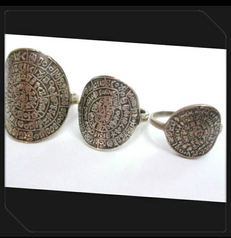 May include: Three silver rings with intricate circular designs. Each ring features a different size and a pattern of symbols and letters.