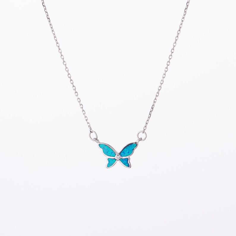 May include: A silver chain necklace with a blue opal butterfly pendant.
