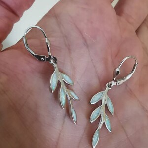 May include: Silver earrings with a delicate branch design featuring white opal stones.