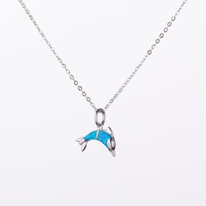 May include: A silver chain necklace with a blue opal dolphin pendant.