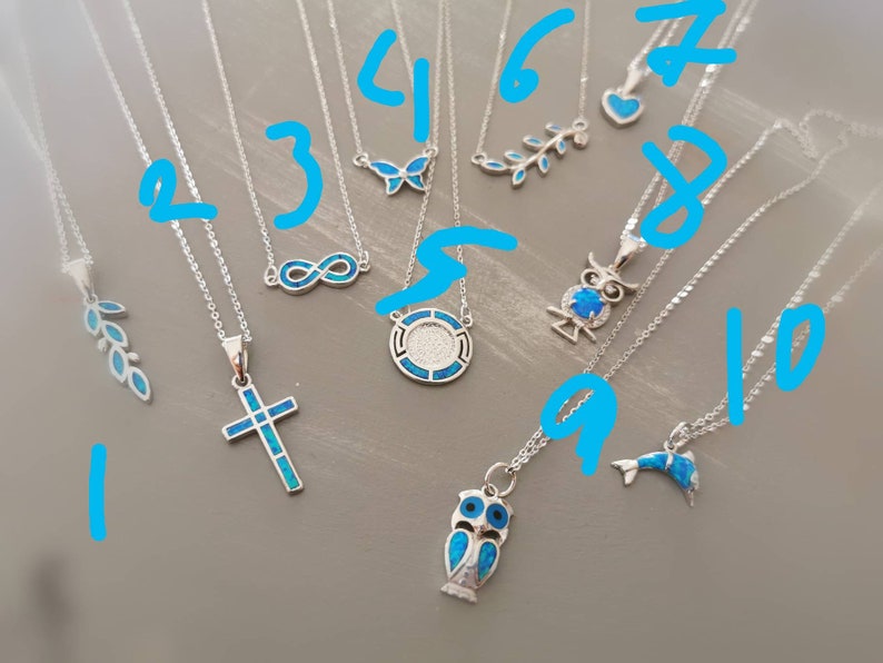 May include: Ten silver necklaces with blue opal pendants. The pendants include a cross, an owl, a butterfly, an infinity symbol, a dolphin, a leaf, and a circle with a design inside.