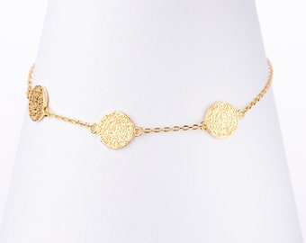 May include: A gold chain bracelet with three round, textured charms. The charms have a detailed, intricate design.
