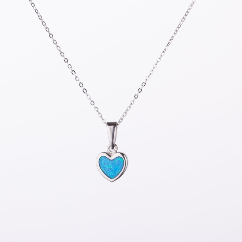 May include: A silver chain necklace with a small heart pendant featuring a blue opal gemstone.