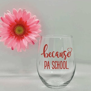 May include: A clear glass wine glass with the text "because PA SCHOOL." in red lettering. A red stethoscope is drawn next to the word "because".