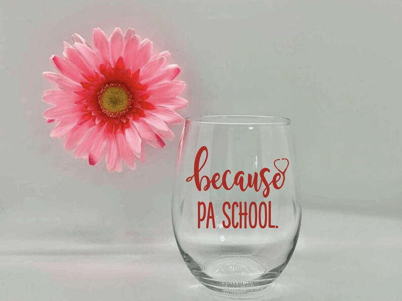 May include: A clear glass wine glass with the text "because PA SCHOOL." in red lettering. A red stethoscope is drawn next to the word "because".