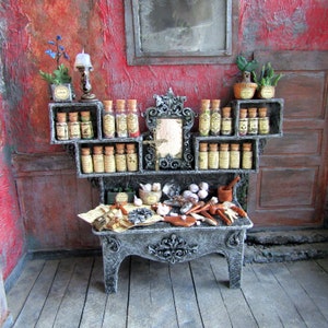 May include: A miniature apothecary display with shelves holding glass bottles with cork stoppers and labels. The display includes a mirror, small plants, and various tools, all set against a red wall.