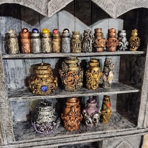 May include: A wooden shelf with multiple small decorative bottles. The bottles are made of glass and have a variety of colors and designs. Some of the bottles have a gold finish, while others have a silver finish. The bottles are arranged in rows on the shelf.