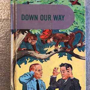 May include: Vintage hardcover book titled "Down Our Way." The cover shows illustrations of monkeys in a tree, a police officer, and a man in a suit. The background is yellow with green foliage and a purple banner with the title.