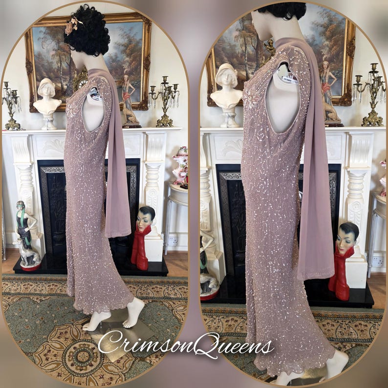 May include: A mauve, floor-length gown with a high neckline and a flowing cape. The dress is embellished with sequins and beads, creating a shimmering effect. The dress is displayed on a mannequin. The text "CrimsonQueens" is at the bottom.