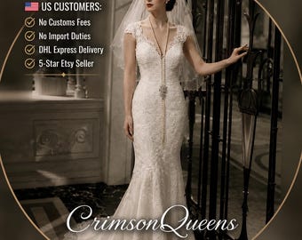 May include: A white lace wedding dress with a V-neckline, cap sleeves, and a fitted bodice that flares into a mermaid silhouette. The dress features intricate floral lace detailing throughout, a long veil, and a long pearl necklace accessory.