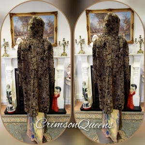 May include: A hooded, long coat with a textured, dark brown and black pattern. The coat is displayed on a mannequin. The bottom of the coat reveals a colorful, patterned fabric. The text "Crimson Queens" is visible at the bottom.