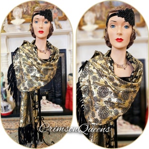May include: A gold and black shawl with a floral pattern and black fringe. The shawl is draped over a mannequin wearing a black dress and a black headband with a jeweled embellishment.