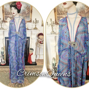 May include: A sheer, floor-length blue and purple patterned dress with a V-neckline and pink trim. The dress is accessorized with a light blue beaded necklace and a gold-toned brooch. The text "Crimson Queens" is visible.
