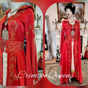 May include: A red hooded gown with gold embroidery and embellishments. The gown has a long skirt and long sleeves. The gown is on a mannequin in a room with a fireplace and other decor.