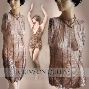 May include: A sheer, light brown dress with vertical beaded strands, displayed on a mannequin. The dress has a high neckline and short sleeves. A gold-toned necklace with a pendant is worn. The text "CRIMSON QUEENS" is at the bottom of the image.