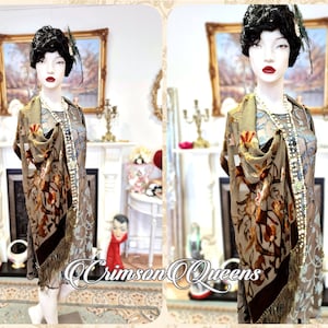 May include: A brown and gold vintage silk shawl with floral embroidery and fringe. The shawl is draped over a mannequin wearing a beaded dress.
