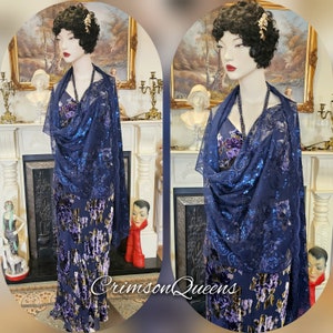 May include: A navy blue sequined shawl with a floral pattern. The shawl is draped over a mannequin wearing a purple velvet dress with a floral pattern.