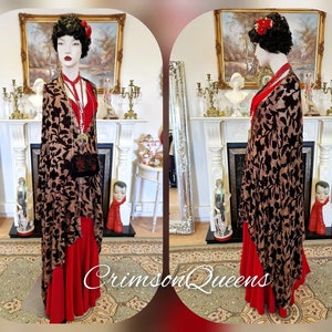 May include: A black and gold patterned velvet shawl with a red dress underneath. The shawl is draped over a mannequin in a vintage style.