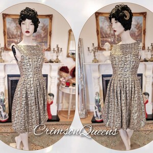 May include: A gold and black tweed dress with a boat neck and a pleated skirt. The dress is on a mannequin in a room with a fireplace.