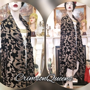 May include: A black and gold velvet shawl with a floral pattern. The shawl is draped over a mannequin and has a fringed edge.