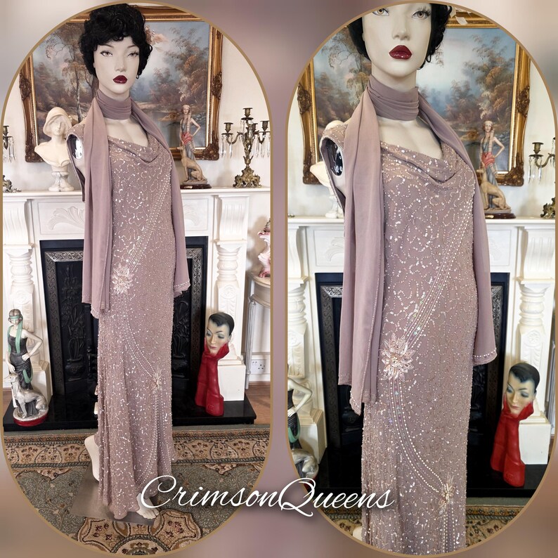 May include: A mauve, floor-length gown with detailed sequin and bead embellishments. The dress has a cowl neckline and is worn with a matching shawl. The text "Crimson Queens" is visible at the bottom of the image. The dress is displayed on a mannequin.
