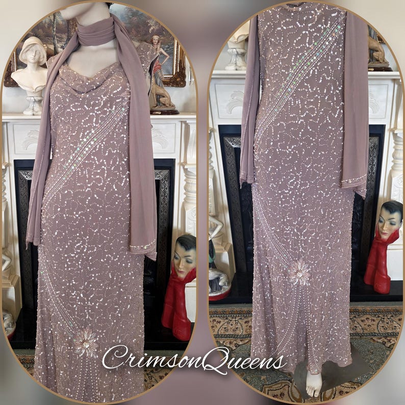 May include: A mauve, floor-length gown with a cowl neckline and long sleeves. The dress is adorned with sequins and beads in a floral design. A matching scarf is draped over the shoulders. The text "Crimson Queens" is visible at the bottom.