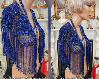May include: A royal blue beaded shawl with fringe, displayed on a mannequin. The shawl is adorned with sequins and intricate beadwork. A matching beaded necklace is also visible. The text "Crimson Queens" is at the bottom of the image.